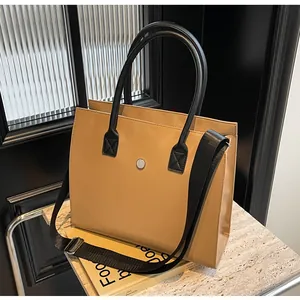 Detail of camel tote bag with black handles on marble stand with elegant textured glass
