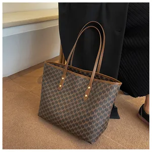 Dettaglio della grande borsa tote marrone con stampa a monogramma e manico in pelle sottile