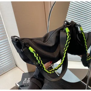 Detail of black nylon crescent bag with neon green woven cord and matte black hardware