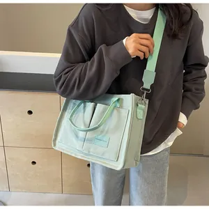Dettaglio della borsa tote in tela verde menta con tasche frontali e tracolla in tessuto
