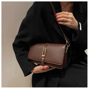 Detail of dark brown leather crossbody bag with a gold rectangular metal buckle