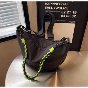 Detail of black nylon crescent bag with neon green woven strap and matte hardware