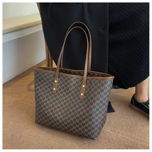 Dettaglio della classica borsa tote con motivo monogramma M marrone e manici in pelle rinforzata