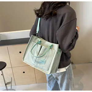 Dettaglio della borsa tote in tela verde chiaro con etichetta laterale e tracolla regolabile