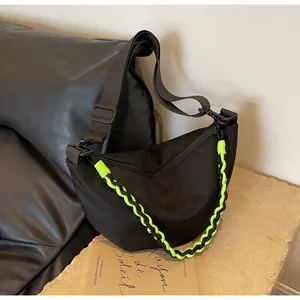 Detail of black nylon dumpling bag featuring a neon green braided chain and wide strap