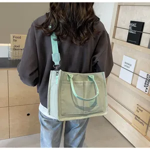 Dettaglio della borsa tote in tela verde menta con tasche frontali e tracolla larga