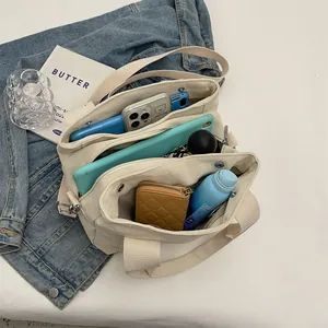 Detail of canvas bag showing multiple compartments holding a tablet, phone and umbrella
