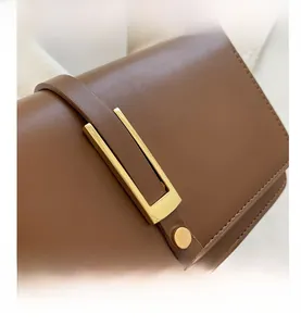 Detail view of a vintage dark brown leather crossbody bag with a sleek gold metal buckle