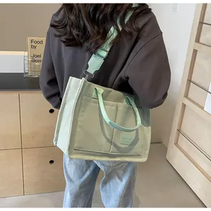 Dettaglio della borsa tote in tela verde menta con tasche frontali e tracolla larga