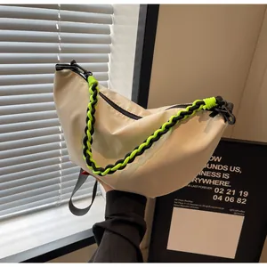 Detail of hobo bag featuring woven neon green rope strap and beige nylon material