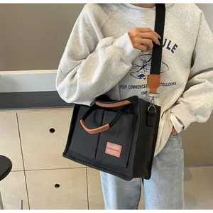 Dettaglio della borsa tote in tela nera con finiture in ecopelle marrone e tasche esterne