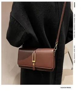 Detail view of a vintage dark brown leather crossbody bag with elegant gold metal hooks