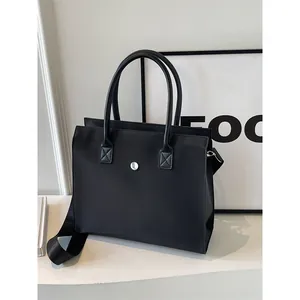 Minimalist black large capacity commuter tote bag with woven shoulder strap and metal buckle