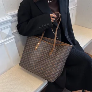 Borsa tote marrone classica con stampa monogramma indossata da modella in abito nero
