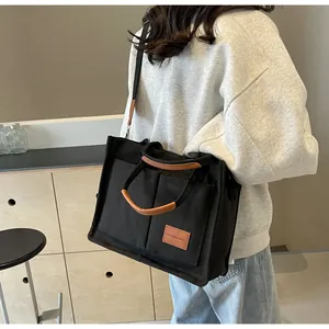 Dettaglio del retro di una modella che indossa una borsa tote nera con etichette in cuoio