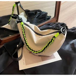 Detail of off-white nylon crescent bag featuring neon green woven rope and adjustable strap
