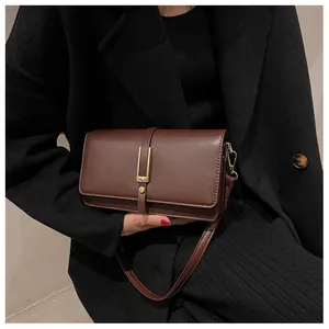 Detail of vintage dark brown leather crossbody bag with golden H-shaped hardware and strap