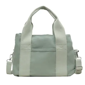 Green canvas handbag with wide top handles and adjustable shoulder strap in front view