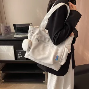 Detailed view of white canvas tote bag with front zipper and round coin purse attachment