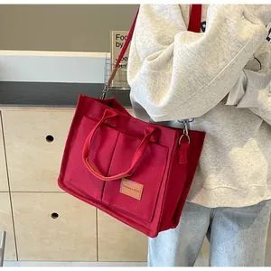 Dettaglio della borsa tote in tela rossa con tasche frontali ed etichetta in pelle a tracolla