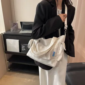 Detail of white canvas tote bag showing side pockets and adjustable shoulder strap