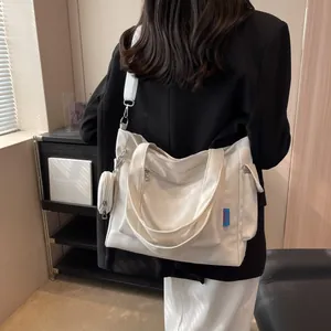 Detail of white canvas tote bag featuring a round coin purse and adjustable strap