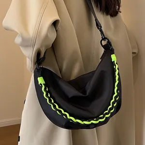 Black nylon crescent crossbody bag with neon green woven rope detail worn by model
