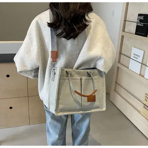 Dettaglio della borsa tote in tela grigia con inserti in pelle marrone indossata da modella