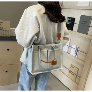 Dettaglio della borsa tote in tela grigio chiaro con finiture in pelle marrone e tasca laterale