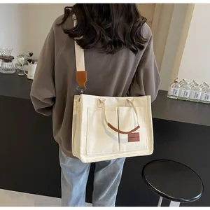 Dettaglio della borsa tote in tela con ampie tasche anteriori ed etichetta in pelle