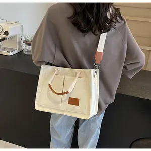 Dettaglio della borsa tote in tela con tasche laterali e targhetta in pelle marrone scuro