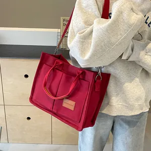 Borsa tote in feltro rosso con cinturini in pelle e tasche, vista laterale modella
