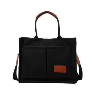 Grande borsa tote in tela nera con tracolla regolabile e finiture in pelle marrone