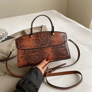 Detailaufnahme der braunen Handtasche mit Schlangenprägung und goldener Hardware