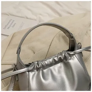 Close-up of metallic silver drawstring bag featuring elegant pleated texture and strap