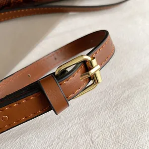 Detailaufnahme des braunen Leder-Schultergurts mit goldener Schnalle und Ziernaht