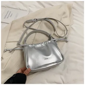 Detailed macro view of silver metallic bag featuring drawstring ruched texture and top handle