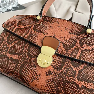 Detailaufnahme einer braunen Handtasche mit Schlangenmuster und polierten Goldbeschlägen