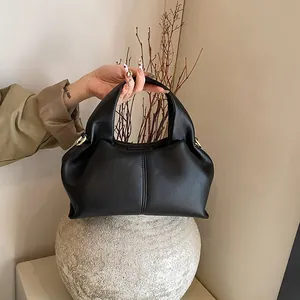 Detail of black lychee grain leather handbag with gold metal hardware and wide handle