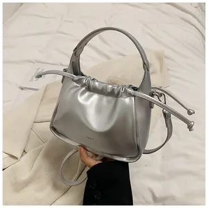 Detail of silver metallic dumpling bag featuring drawstring pleats and a round handle