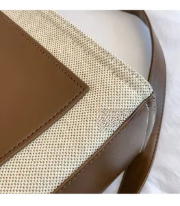 Close-up of contrast stitching on canvas tote bag with brown leather trim detailing