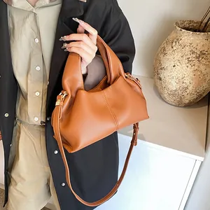 Detail view of caramel brown lychee leather handbag with pleated design and gold hardware