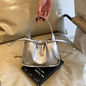 Detail of silver metallic cloud bag featuring drawstring pleats and side tassels