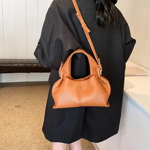 Brown pleated cloud bag shown with an adjustable shoulder strap on a model