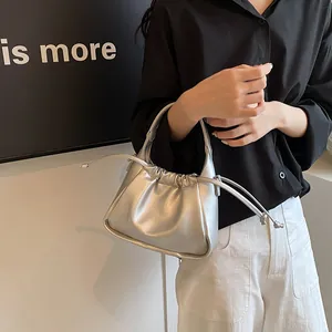 Close-up of metallic silver drawstring dumpling bag with circular metal handle detail