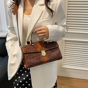 Detailaufnahme der braunen Handtasche mit Schlangenmuster und goldenem Drehverschluss