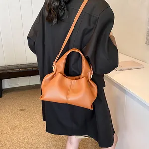 Caramel leather crossbody bag with pleated texture shown on a minimalist model