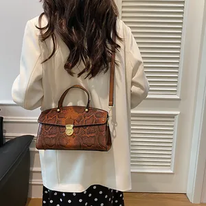 Detailansicht der braunen Handtasche mit Schlangenmuster, Goldschloss und Schultergurt