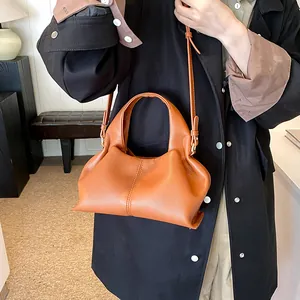 Detail of caramel pleated cloud bag in lychee pattern leather with golden hardware