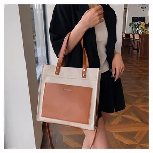 Detail of canvas and leather tote bag featuring brown front pocket and Mycare logo